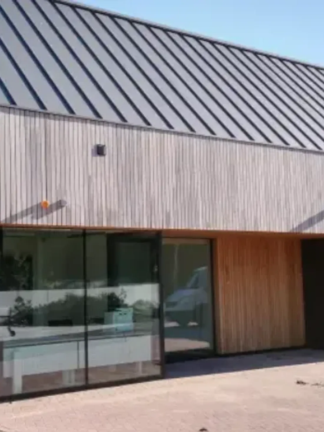 Zinklook langs een bedrijfsgebouw, met licht hout ernaast