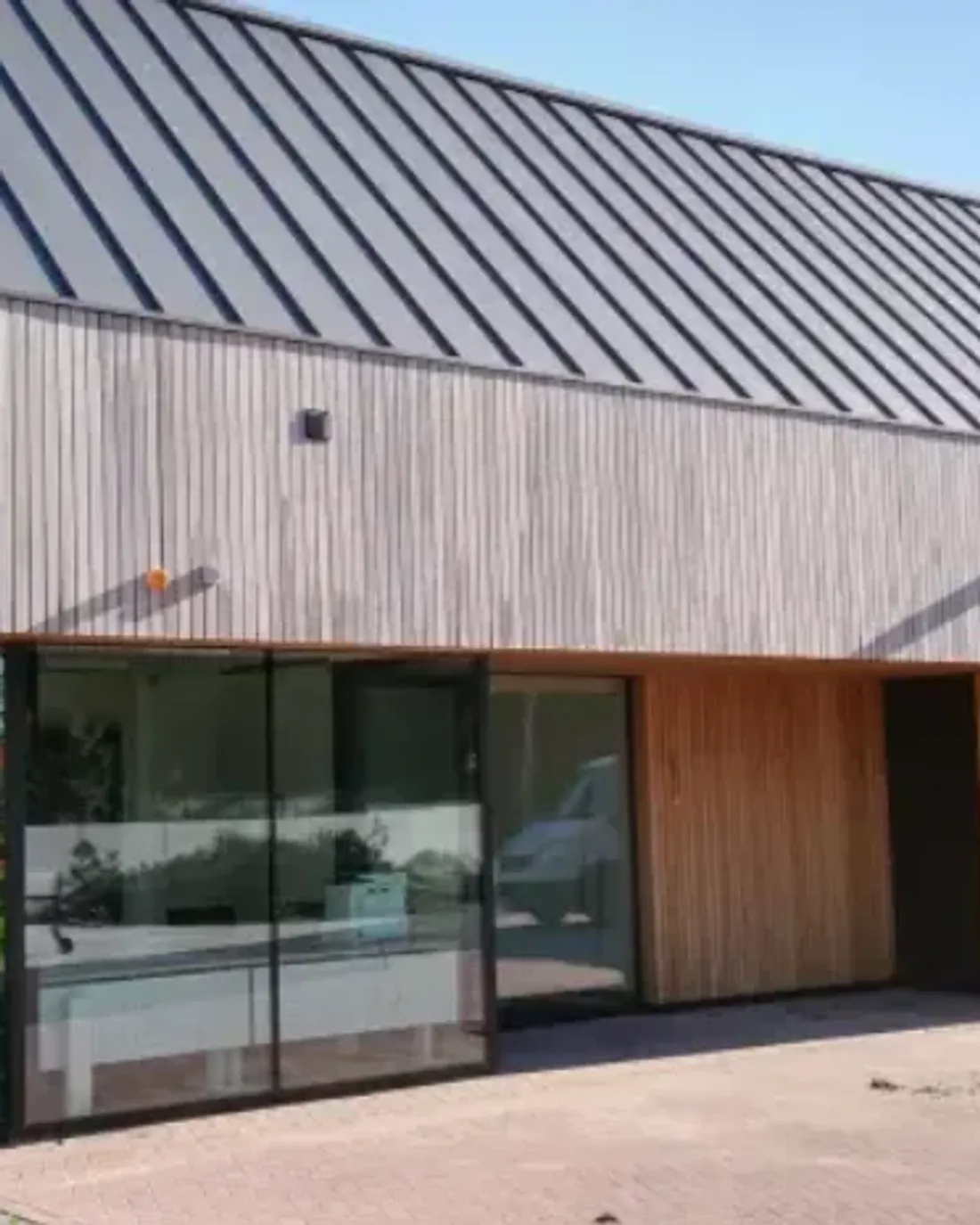 Een bedrijfsgebouw met zinklook op het dak en hout in de gevel